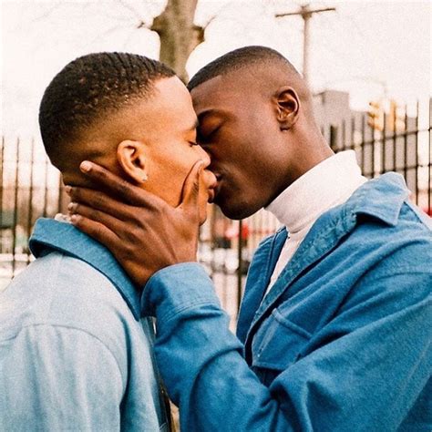 two men are kissing each other in front of a fence