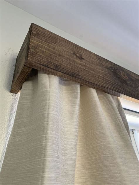 a wooden beam is hanging from the side of a curtain in front of a window