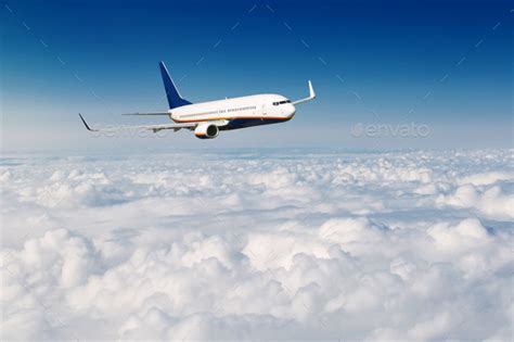 Commercial airplane flying above clouds on blue sky background. Stock Photo by Vladdeep