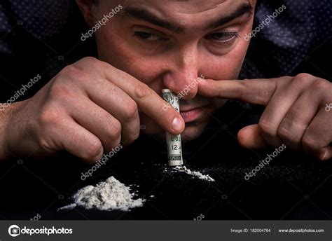 Junkie man snorting cocaine powder with rolled banknote — Stock Photo © andriano_cz #182004784