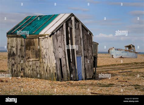 An old dilapidated wooden fishermen's beach hut with boat in background Stock Photo - Alamy