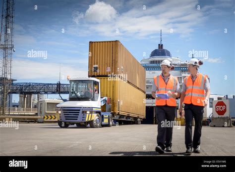 Port workers and truck unloading shipping containers from ship to port Stock Photo - Alamy