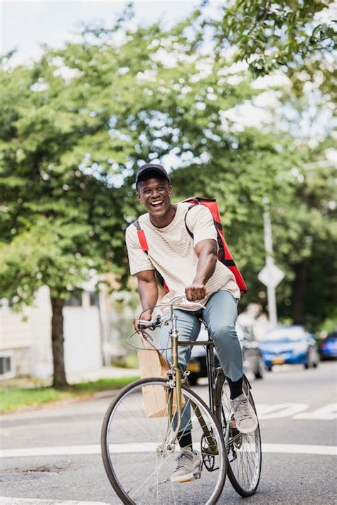 Smiling Courier with Backpack Riding Bike · Free Stock Photo