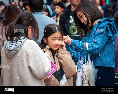 Two japanese teens help their friend fit newly bought earrings at ...