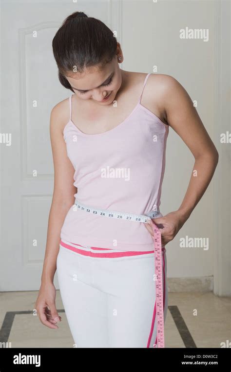 Woman measuring her waist with a tape measure Stock Photo - Alamy