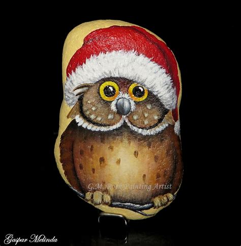 an owl with a santa hat painted on it's face is sitting in front of a black background