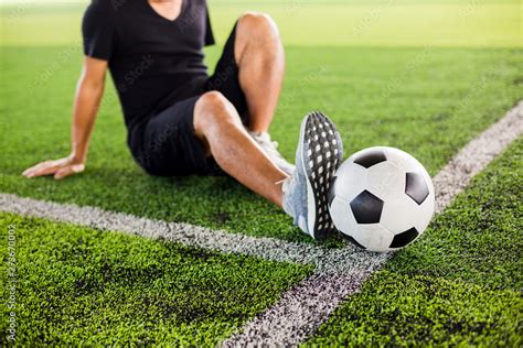 Soccer ball on green artificial turf with the player is stretch the ...