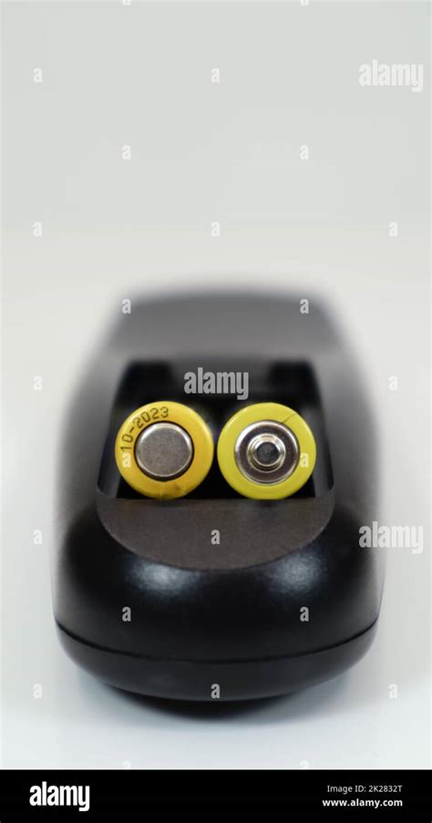 Black remote control with yellow AAA batteries on a white background. Battery replacement, spare ...