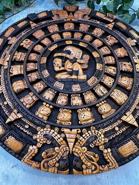 an intricately carved circular object with figures on it's sides and leaves in the background