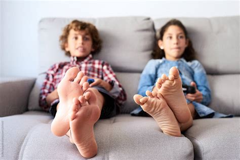 "Barefoot Kids On Sofa Gaming" by Stocksy Contributor "Guille Faingold" - Stocksy