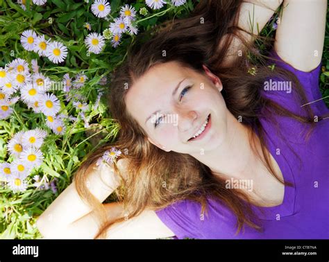 Teen girl lying in grass with flowers Stock Photo - Alamy