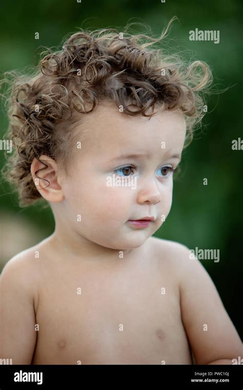 Beautiful baby with curly hair in the garden without t-shirt Stock Photo - Alamy