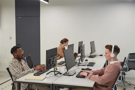 Premium Photo | Wide angle view at group of young people using computers while working in office ...