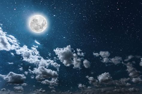 the full moon shines brightly in the night sky with clouds and stars above it