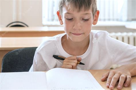 Premium Photo | A focused boy doing homework writing text in a notebook at the table cute ...