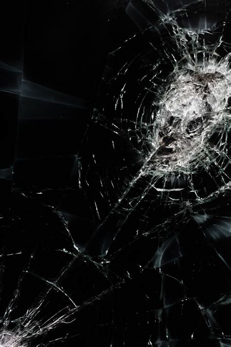 shattered glass in the dark with some light coming from it's center and ...