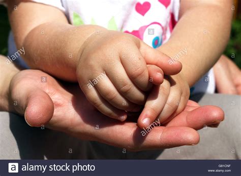 Women's hand holding little baby' hands Stock Photo - Alamy