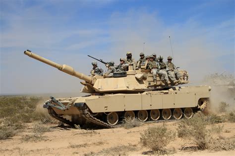 US Soldiers riding on top of an M1A2 Abrams tank during a Combined Arms Live-Fire Exercise ...