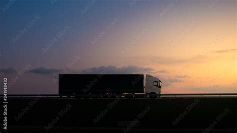 Silhouette of a truck on road at sunset.Semi truck trailer silhouette with setting sun.Delivery ...