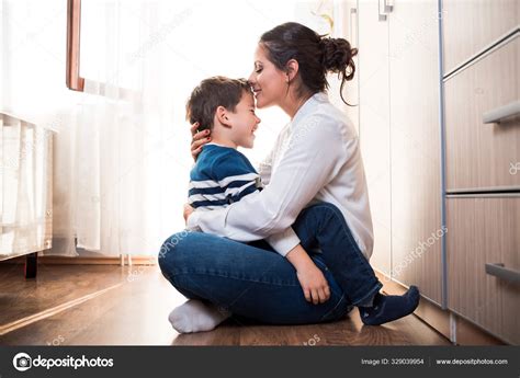 Mom and her son hugging each other. Mom is kissing her kid in the forehead. Stock Photo by ...