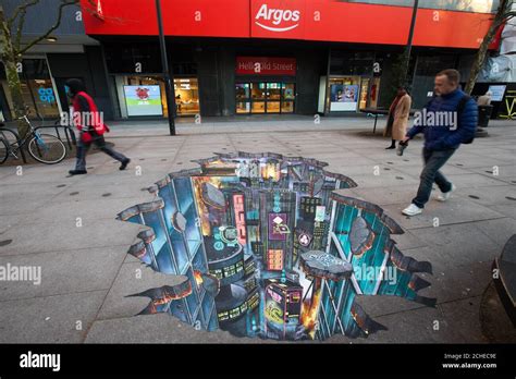 EDITORIAL USE ONLY Passers-by look at a piece of 3D street art is unveiled outside Argos in ...