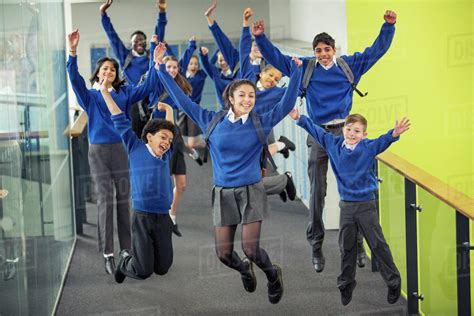 Enthusiastic high school students wearing school uniforms smiling and ...