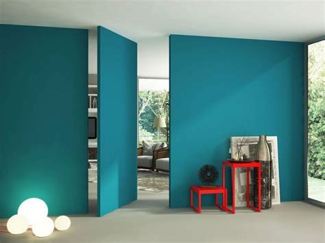 a room with blue walls and two red tables in the corner, near an open door