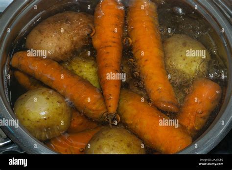 Potatoes and carrots boiling in a pot with hot water. preparing ingredients for salad Stock ...