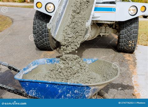 A Mixer Truck Pours Concrete into a Wheelbarrow at a Construction Site ...