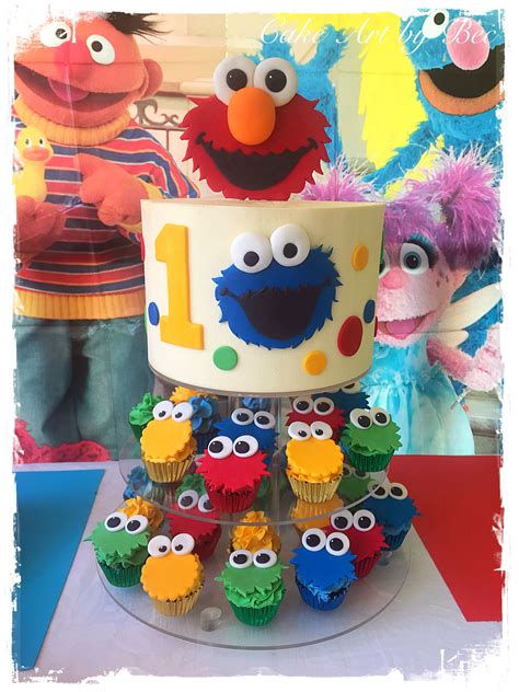 the birthday cake is decorated with cupcakes and sesame street characters