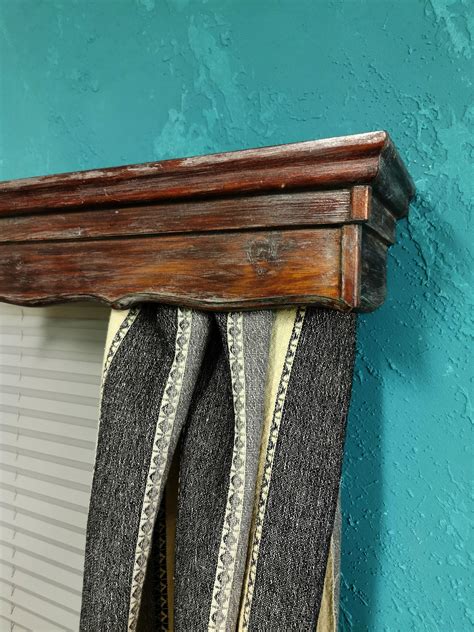 a pair of jeans hanging from a wooden rack on a wall with blue paint ...