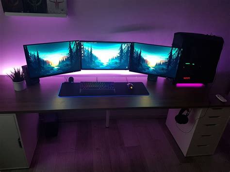 three computer monitors sitting on top of a desk in front of a purple ...