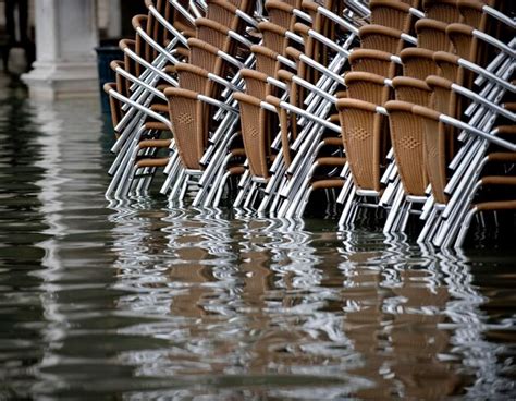 Premium Photo | Brown stacked chairs on water filled walkway during flood at piazza san marco