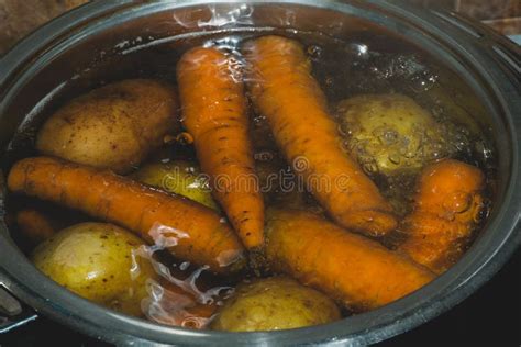 Potatoes and Carrots Boiling in a Pot with Hot Water. Preparing Ingredients for Salad Stock ...