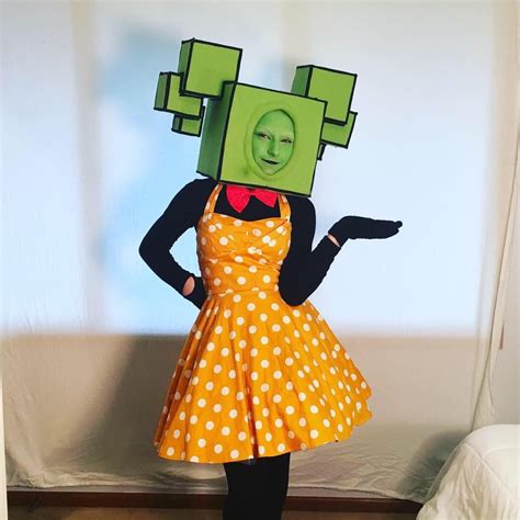 a woman in a yellow polka dot dress and green paper head