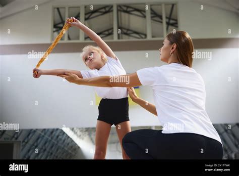 Coaching. Beginner gymnastics athletes doing exercises with gymnastics equipment at sports gym ...