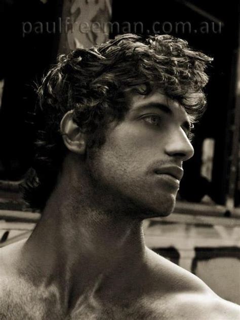 a man with curly hair and no shirt is looking off to the side in black and white