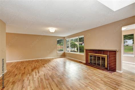 Empty living room interior with brick fireplace and hardwood floor ...