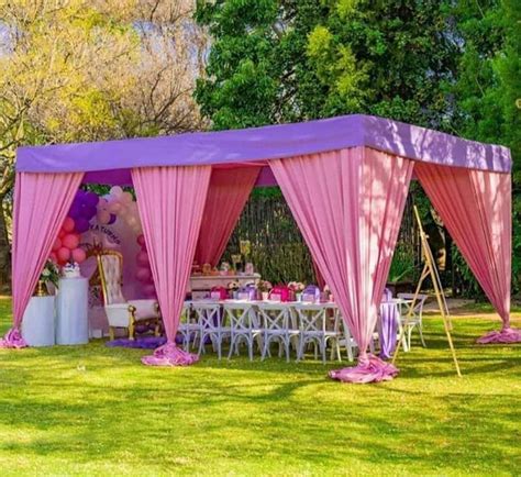 a pink tent set up in the middle of a field with tables and chairs under it