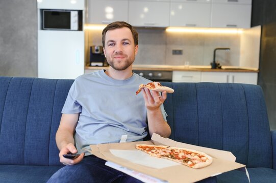 Man eating pizza having a takeaway at home relaxing resting