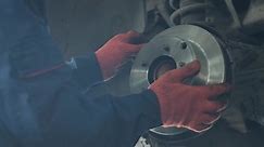 car mechanic replacing car wheel brake shoes of lifted automobile at repair service station