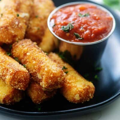 low carb mozzarella sticks on black plate.