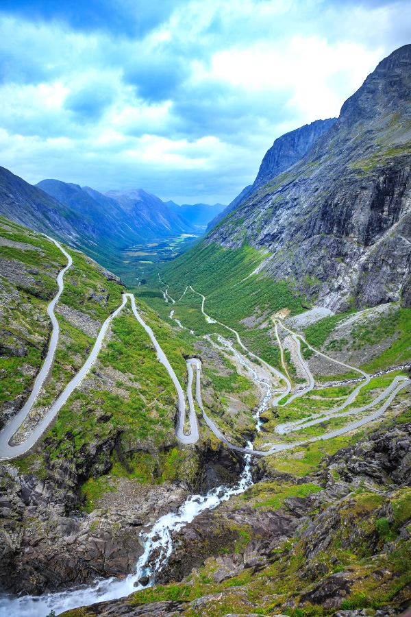 A road with many hairpin bends on the side of a wooded mountain