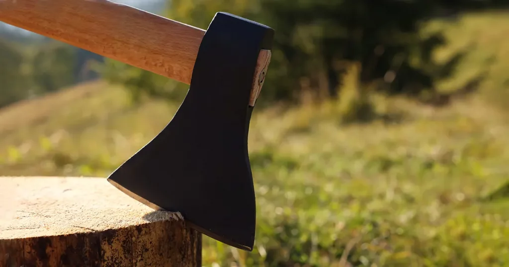 Tree stump with axe outdoors, closeup. Space for text