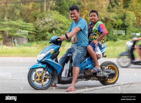 A Thai father and son, sat on a modified, custom motor scooter with extended swing arm and gold ...