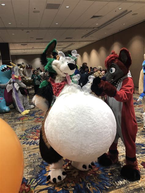 This fursuit with a giant belly with condom balloon animals at the inflatables panel in a ...