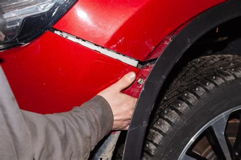 Premium Photo | The hand of a man putting on or removing the front bumper from a red modern car ...