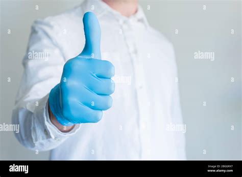 Man in blue medical glove showing approval thumbs up sign on white background with copy space ...