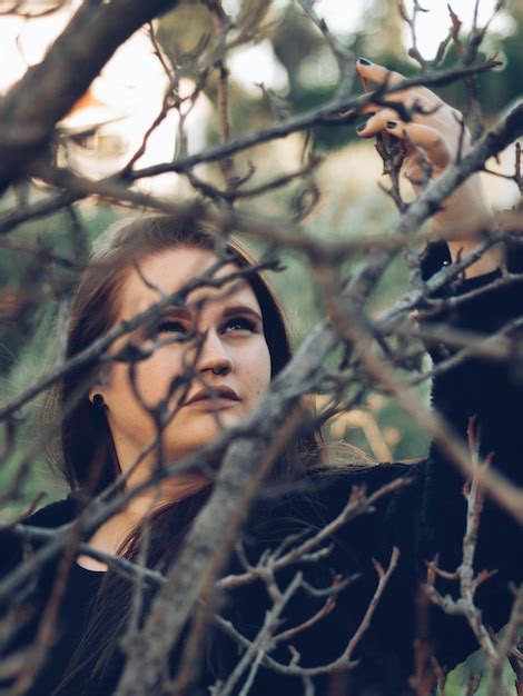 Premium Photo | Young woman holding bare tree branch in forest