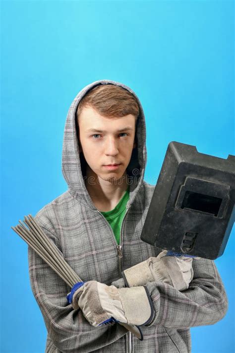 Young Welder with Electrodes and Welding Shield on a Blue Background Stock Photo - Image of ...